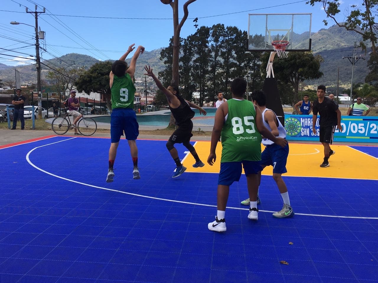 Jugador lanzando al aro en un partido de baloncesto al aire libre